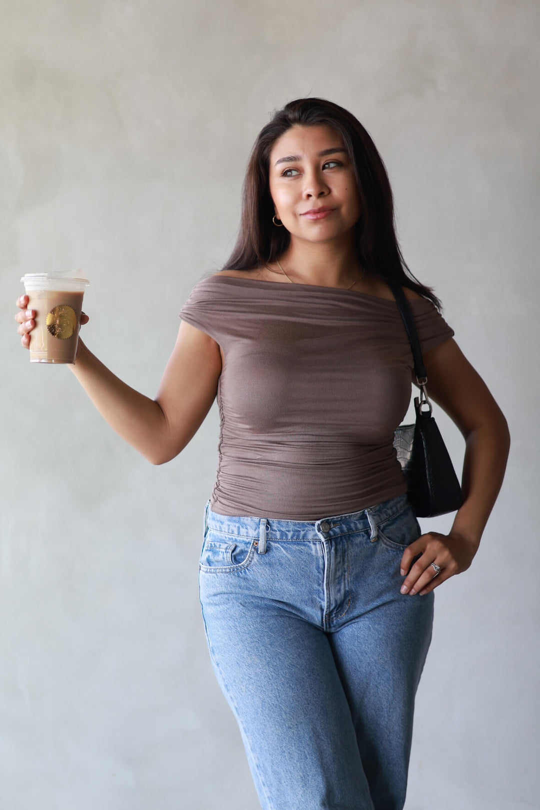 girl wearing a brown top paired with jeans and enjoying a iced latte