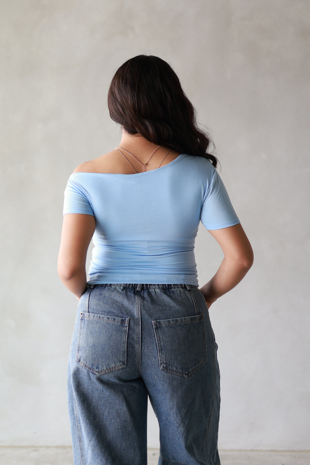 the back of a blue off the shoulder basic top