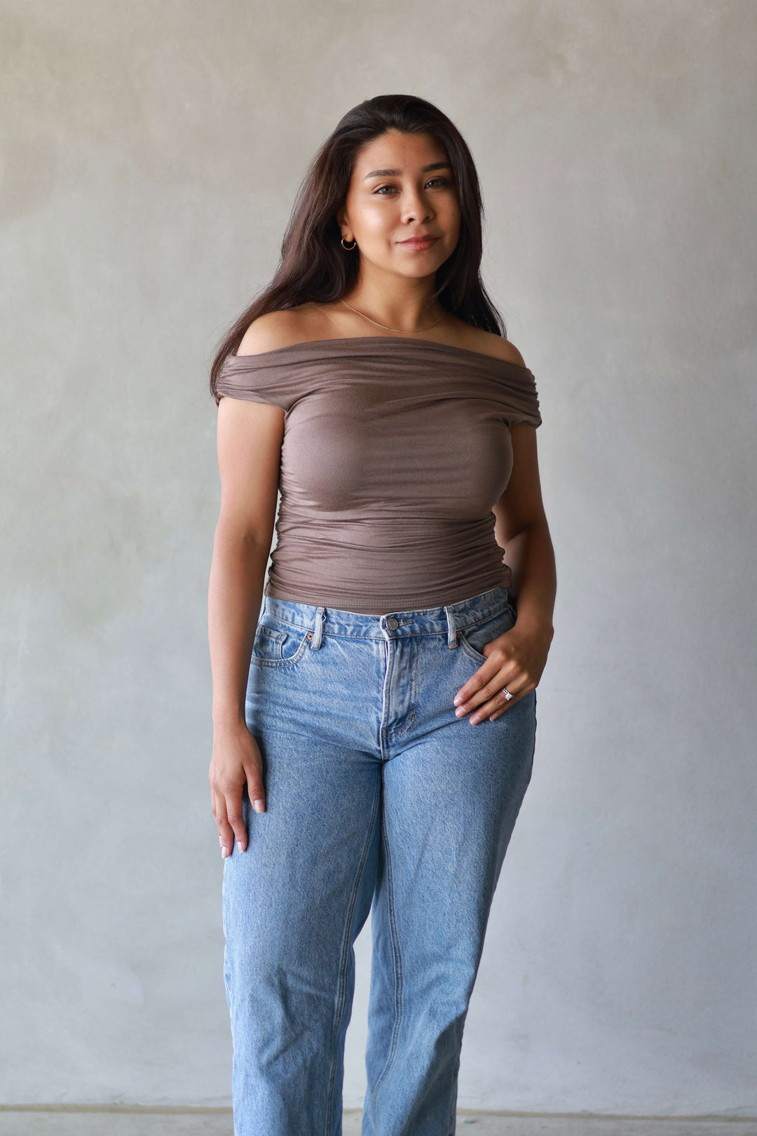 women wearing a brown asymmetrical top with jeans